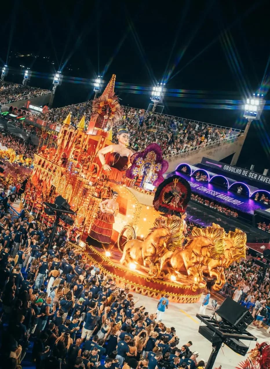 Desfile de Carnaval iluminado com público acompanhando o cortejo